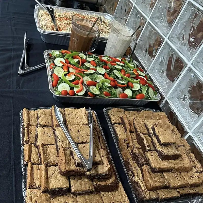 Catering spread with a tray of brownies and a tossed salad