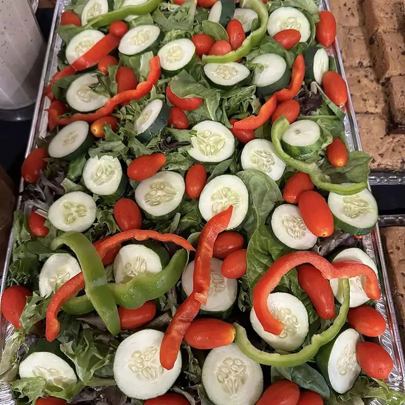 Catering pan of tossed salad with cucumbers and peppers