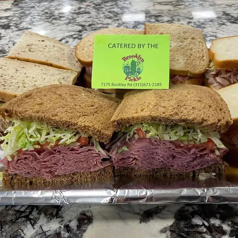 Catering tray of half sandwiches on rye and wheat with a Brooklyn Pickle catering card
