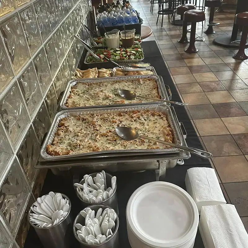 Catering buffet set up with hot pans, plates, and utensils