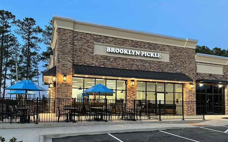 Brooklyn Pickle Southern Pines, brick storefront with blue patio umbrellas